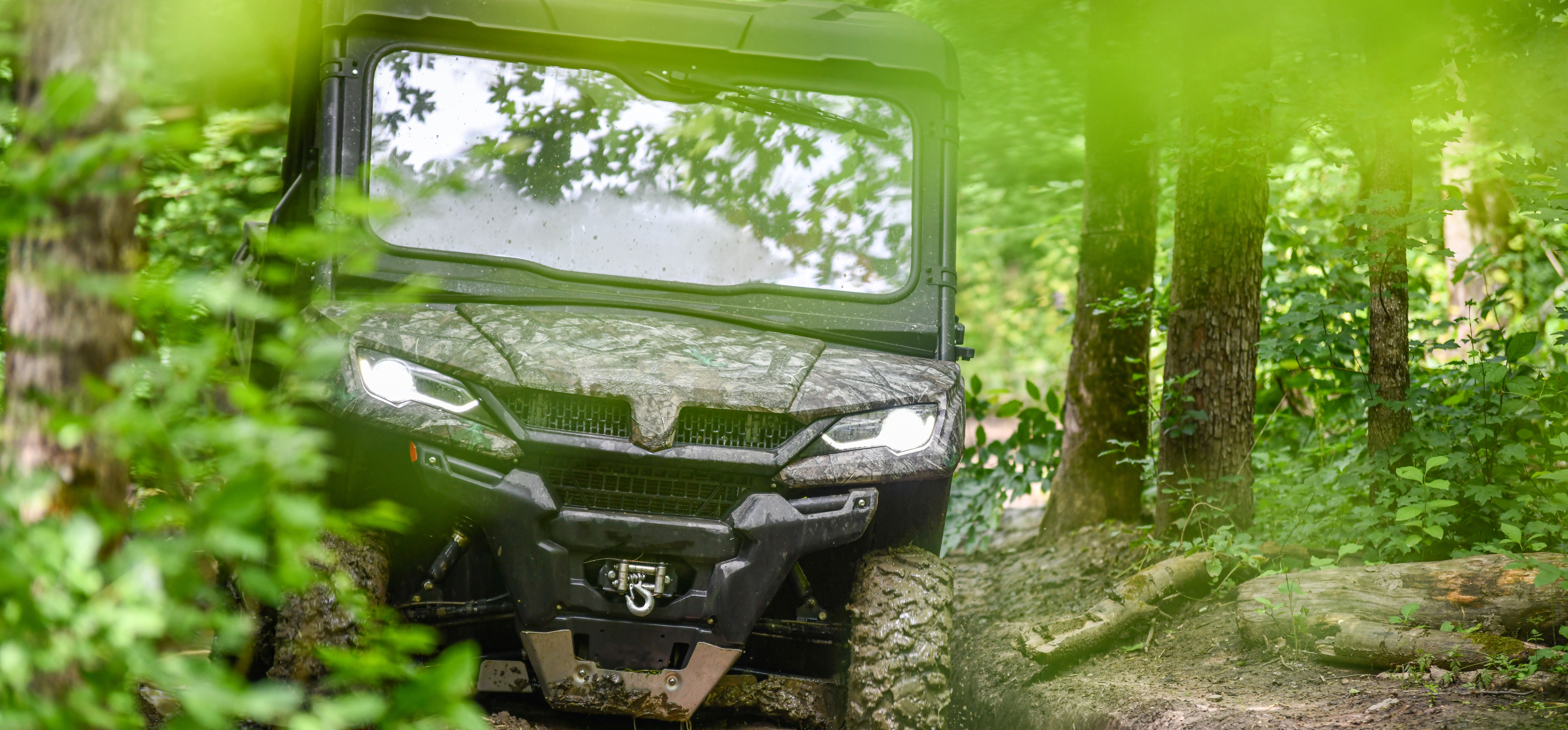 Camouflage side-by-side driving on a trail through the woods